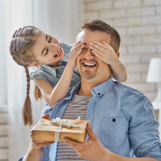 Hijos entregando un regalo personalizado a su padre emocionado, concepto de regalos únicos para el Día del Padre en Regalo Grabado.