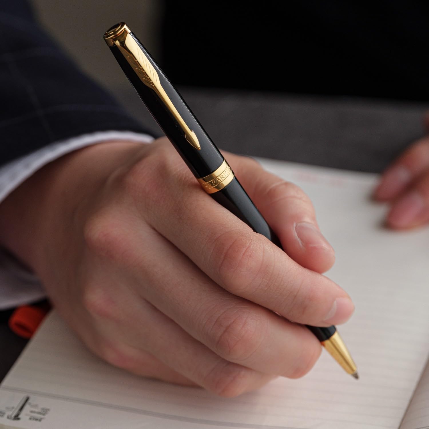 Persona escribiendo con un bolígrafo Parker Sonnet personalizado negro brillo con detalles dorados